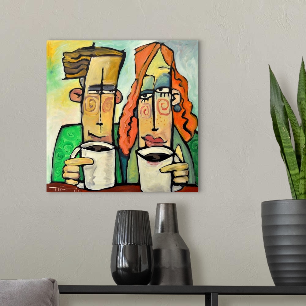 A modern room featuring Square painting of two cartoon like figures enjoying mugs of coffee.