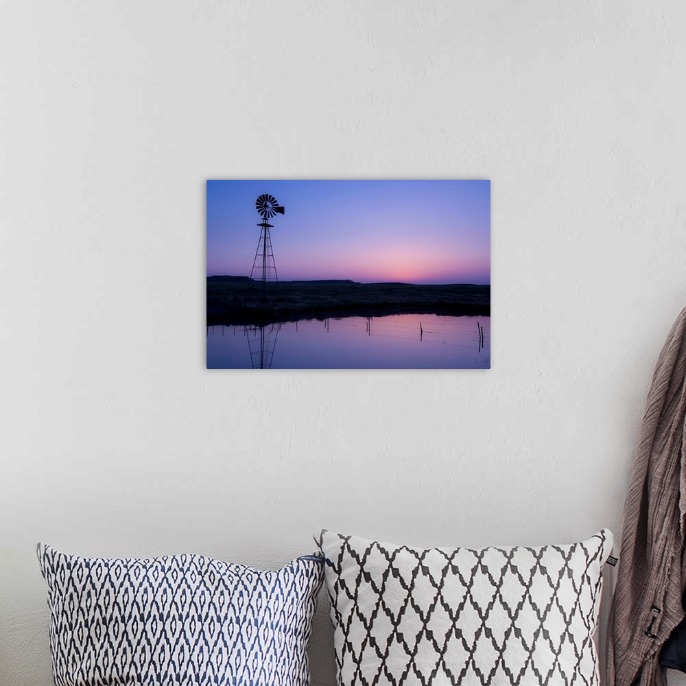A bohemian room featuring windmill in by the water at sunset