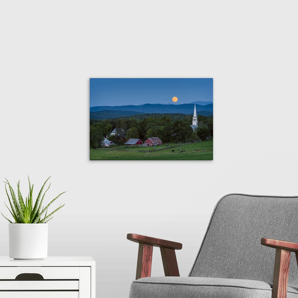 A modern room featuring A photograph of a small village in the countryside seen at night under a clear sky and a full moon.