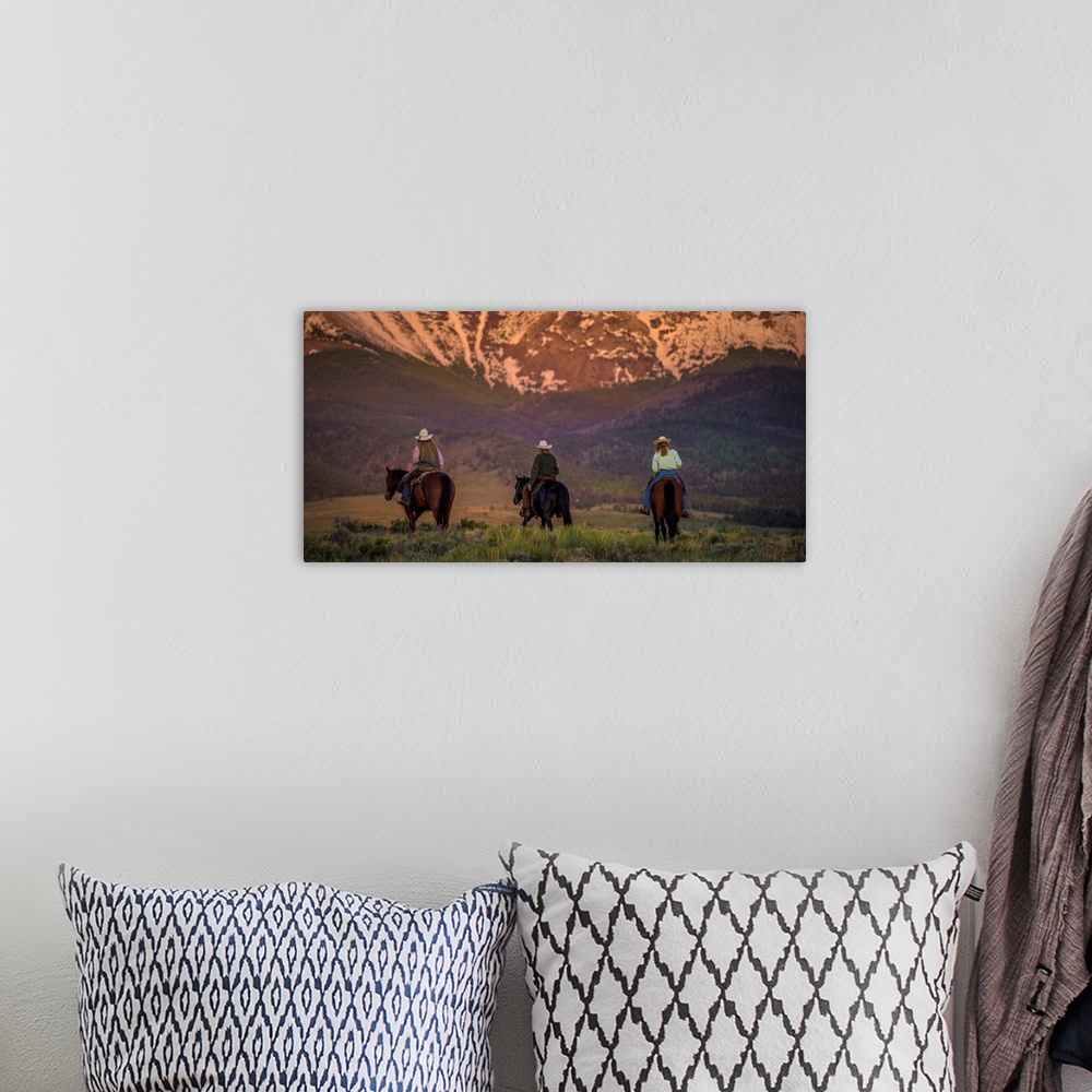 A bohemian room featuring Photograph of three cowgirls on horseback from behind, heading towards the mountains at sunset.