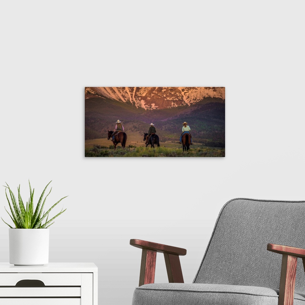 A modern room featuring Photograph of three cowgirls on horseback from behind, heading towards the mountains at sunset.