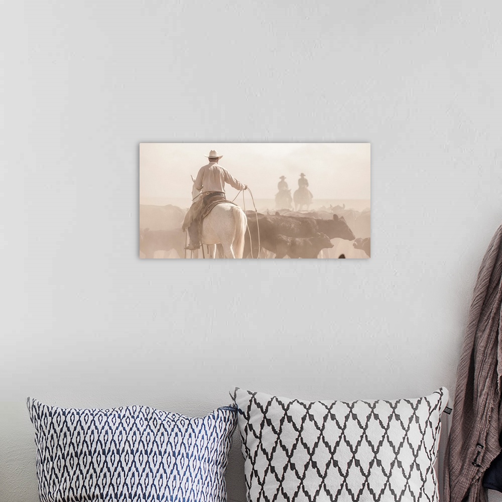 A bohemian room featuring Photograph of a cowboy with a lasso herding cattle with two other people on horseback in the dust...