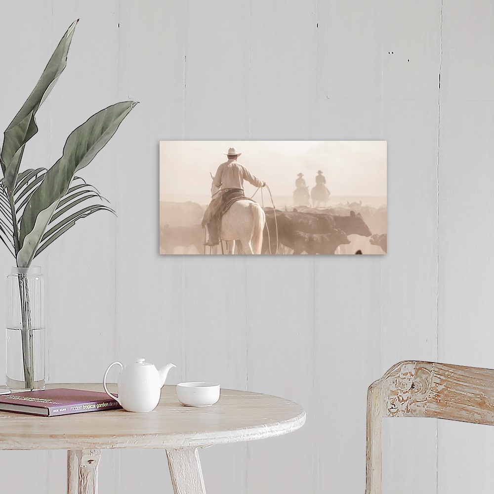 A farmhouse room featuring Photograph of a cowboy with a lasso herding cattle with two other people on horseback in the dust...