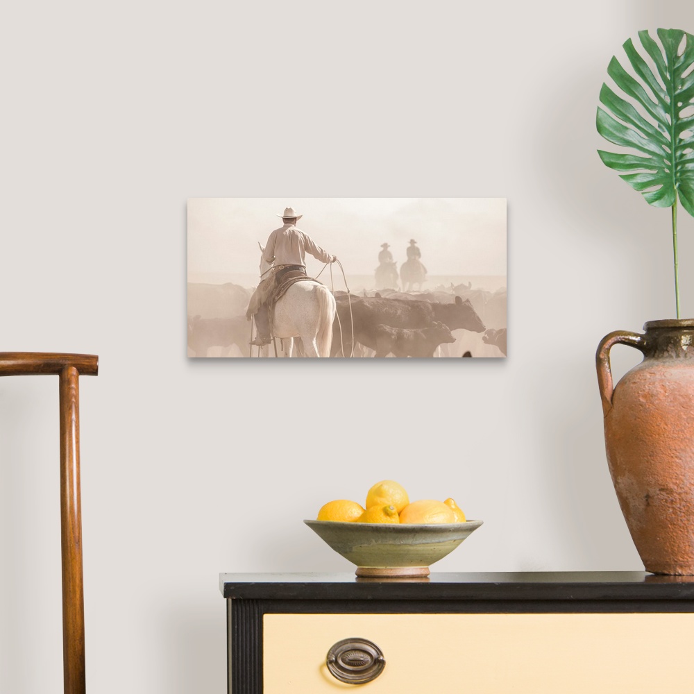 A traditional room featuring Photograph of a cowboy with a lasso herding cattle with two other people on horseback in the dust...