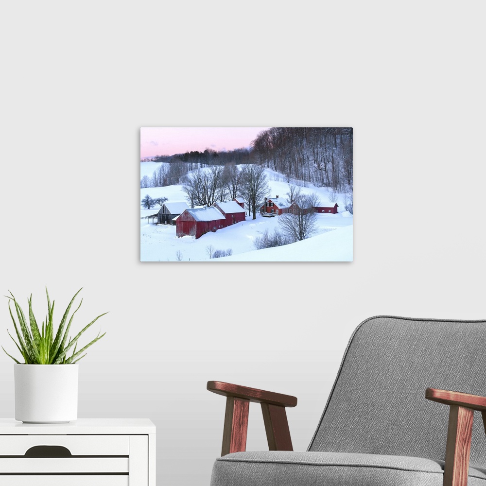 A modern room featuring Photograph of a snowy rolling hills with red buildings and bare Winter trees at sunrise.