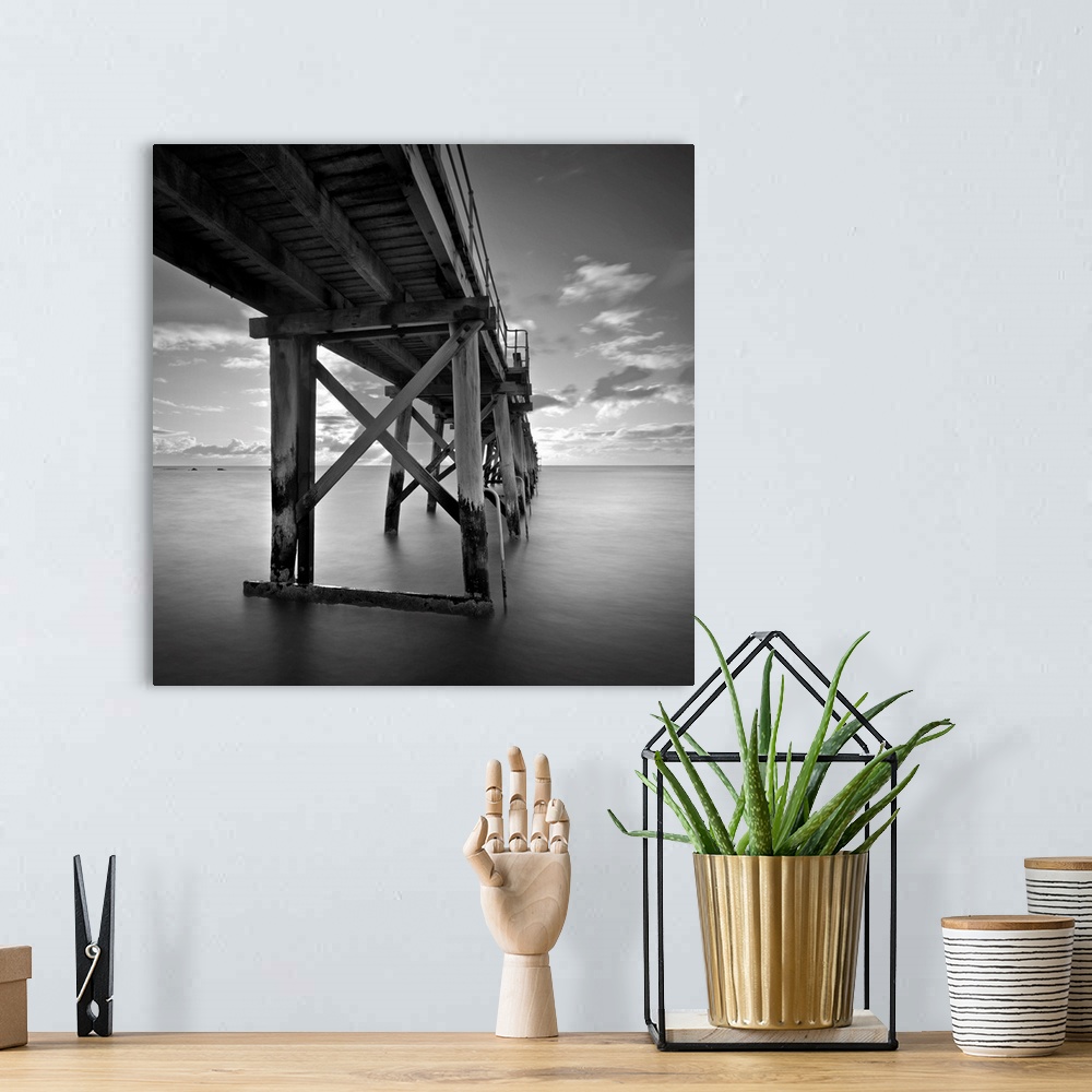 A bohemian room featuring A black and white photograph of a pier jetting out over the ocean.