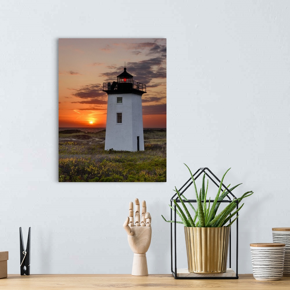 A bohemian room featuring Photograph of a square, white lighthouse with a bright orange sunset in the background.