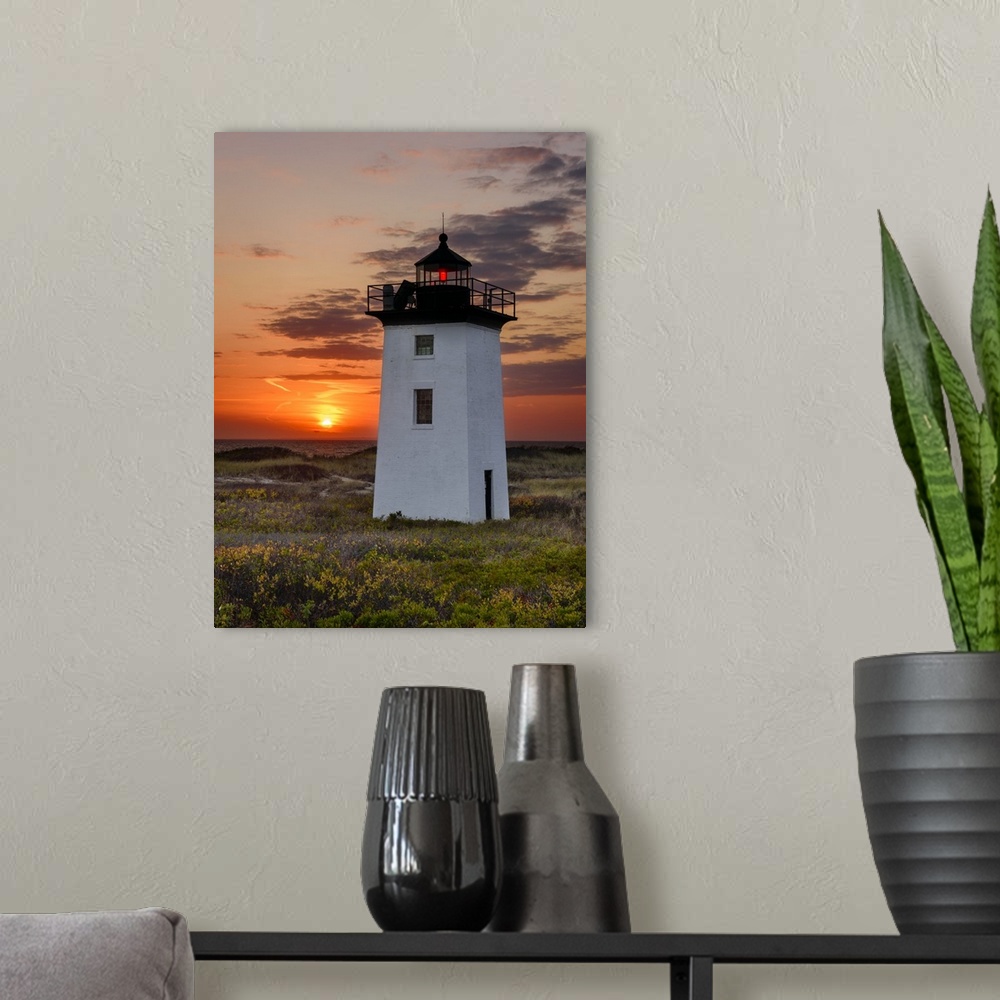 A modern room featuring Photograph of a square, white lighthouse with a bright orange sunset in the background.