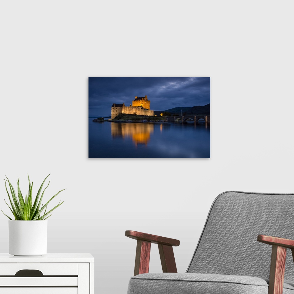 A modern room featuring A photograph of the Eilean Donan castle in Scotland seen at night.
