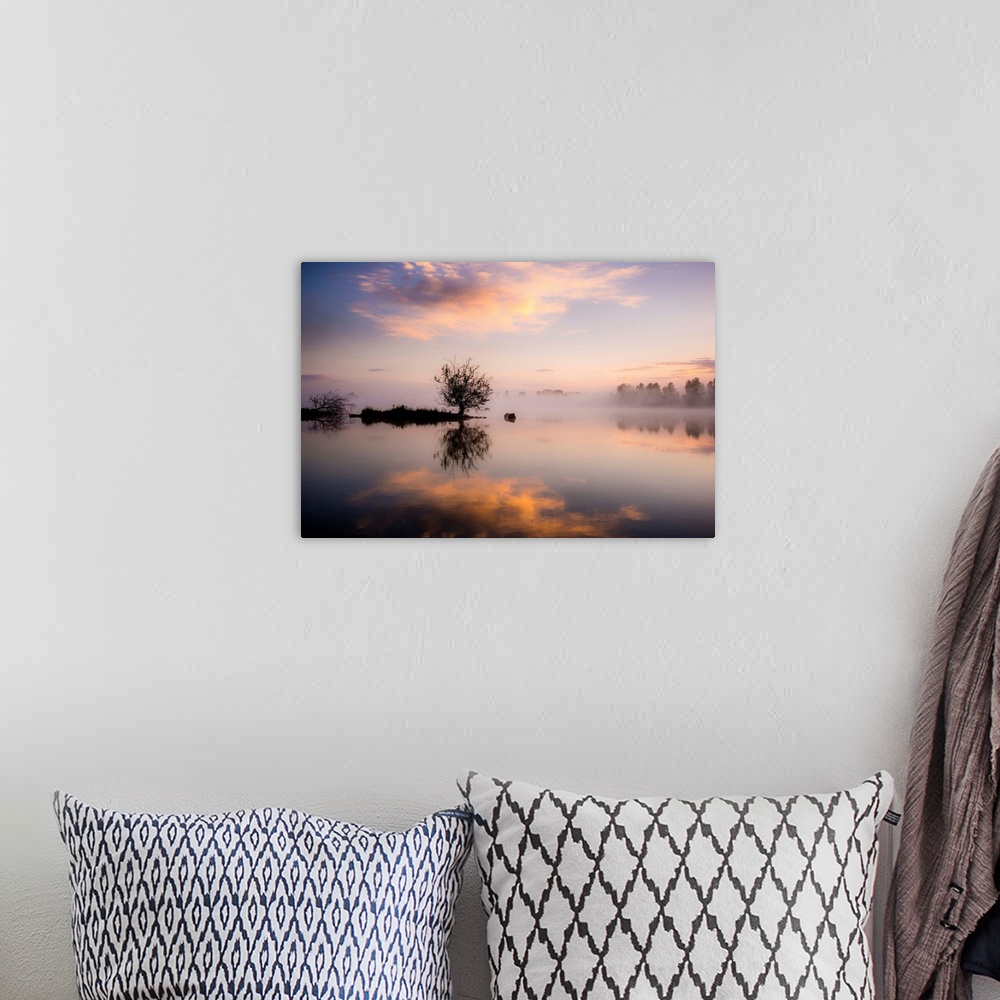 A bohemian room featuring A photograph of a foggy landscape with silhouetted trees being reflected in the water below.