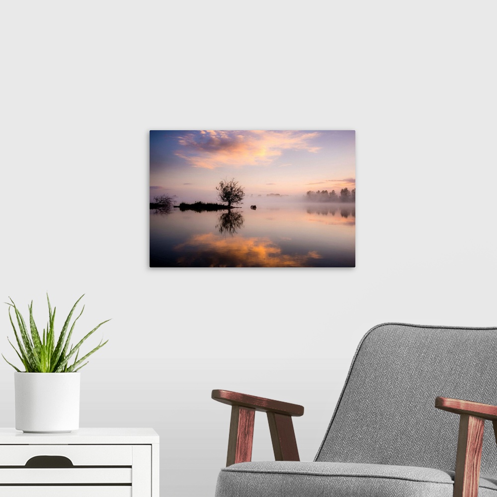 A modern room featuring A photograph of a foggy landscape with silhouetted trees being reflected in the water below.