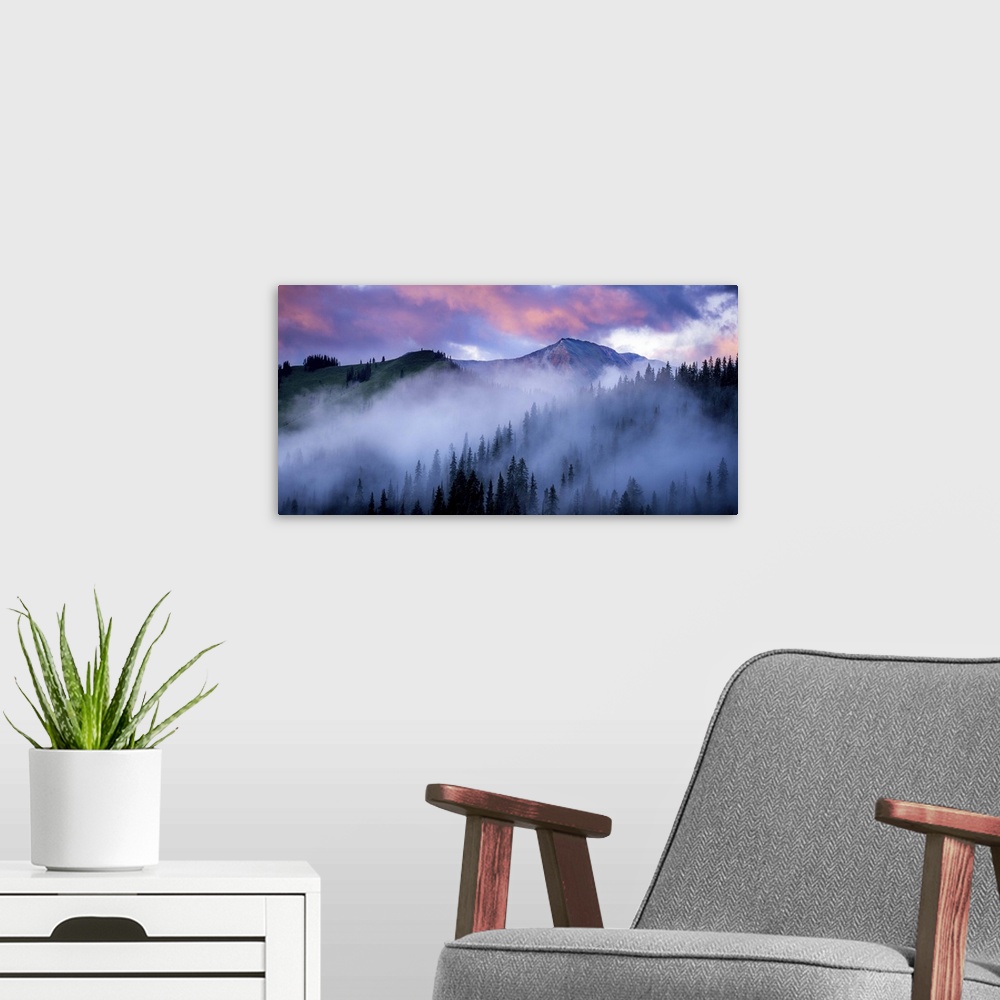 A modern room featuring A photograph of mountain under dramatic clouds illuminated by the sunset.