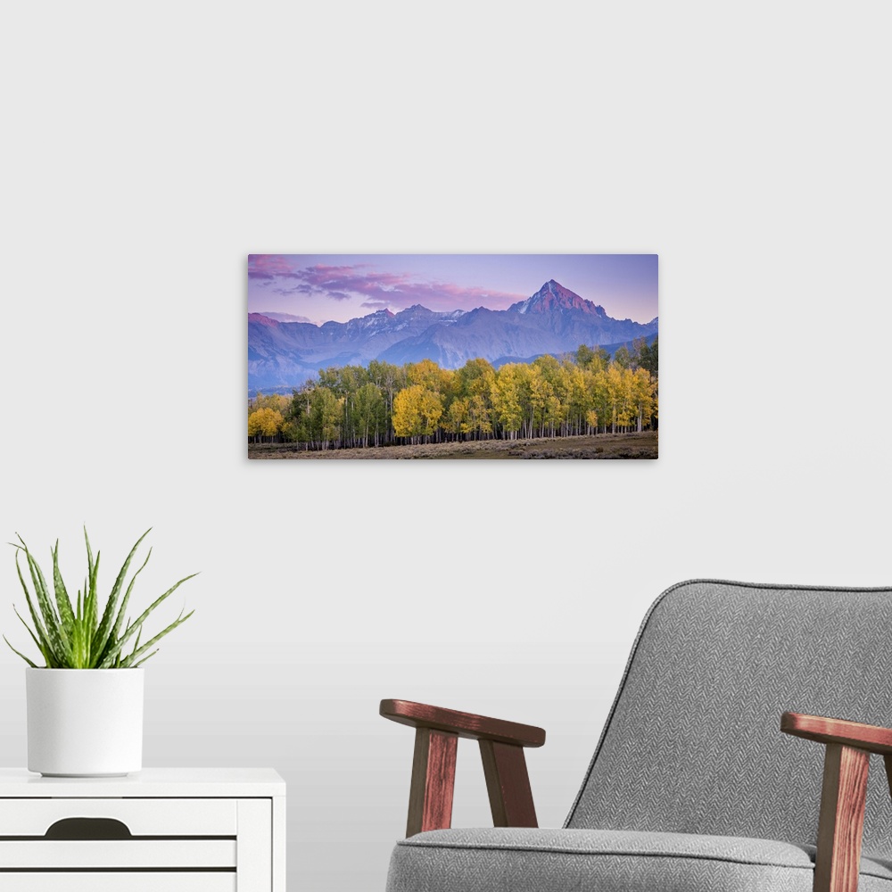 A modern room featuring A photograph of purple mountains seen in the distance with a forest in autumn foliage in the fore...