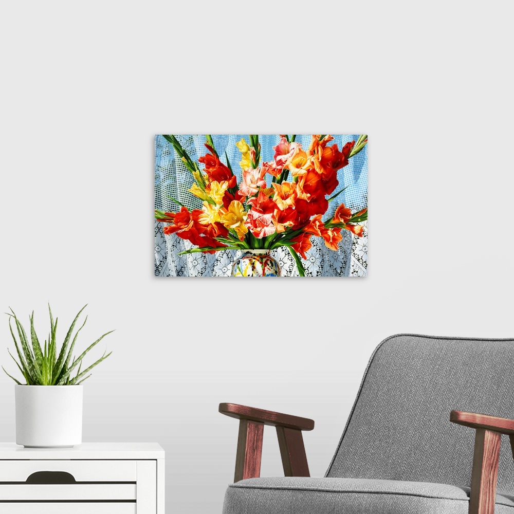 A modern room featuring Contemporary vivid realistic still-life painting of bright red orange and yellow flowers in a mul...