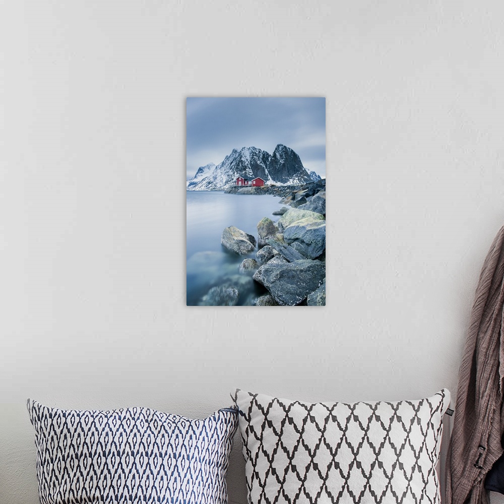 A bohemian room featuring A photograph of a Norwegian red cabin with gray mountain boulders all around.