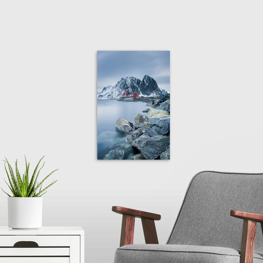 A modern room featuring A photograph of a Norwegian red cabin with gray mountain boulders all around.