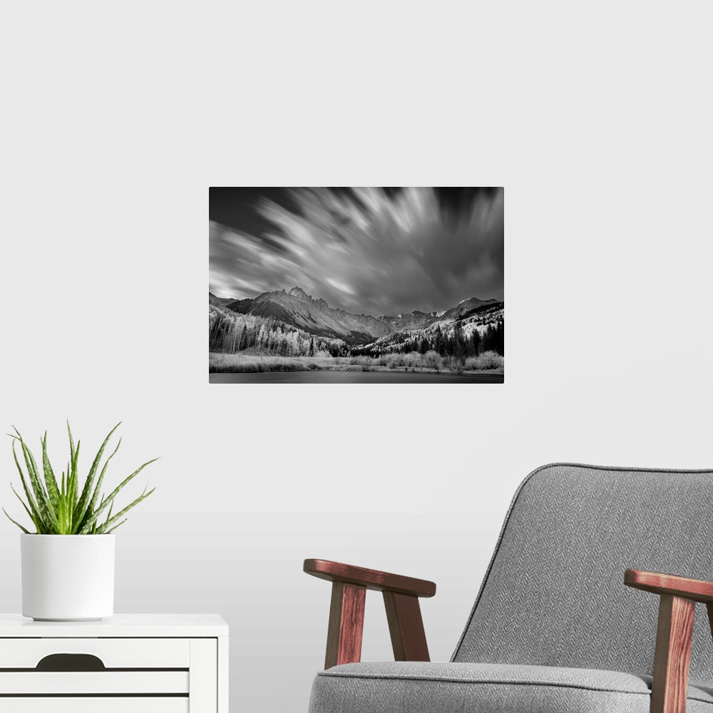 A modern room featuring Black and white landscape photograph of a lake in front of a mountain range with blurred moving c...