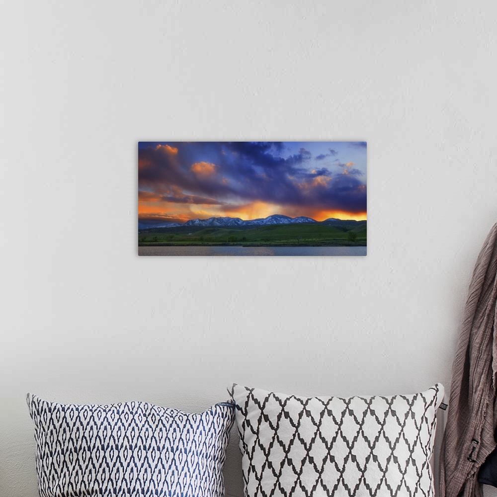 A bohemian room featuring Vivid clouds at sunset over a mountain range.