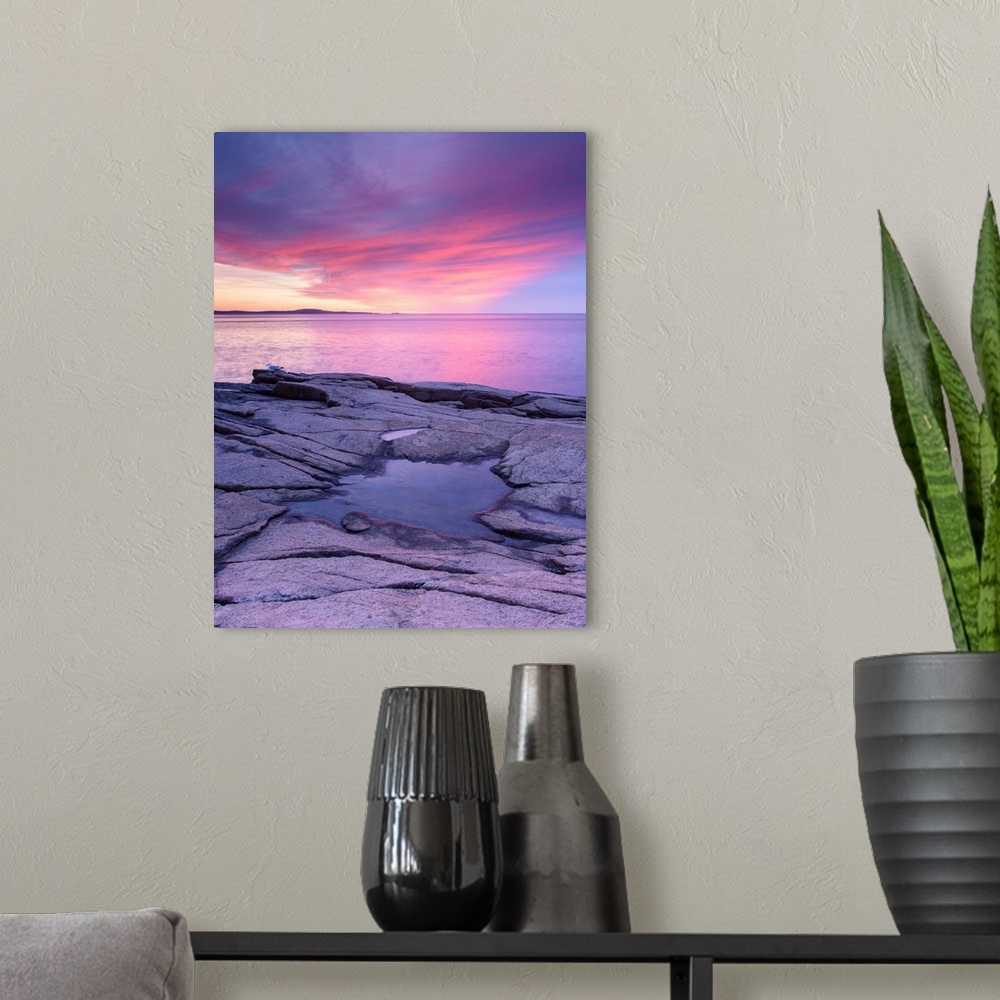 A modern room featuring Pink and purple photograph of a beautiful sunset over the water and a frozen puddle of water on t...