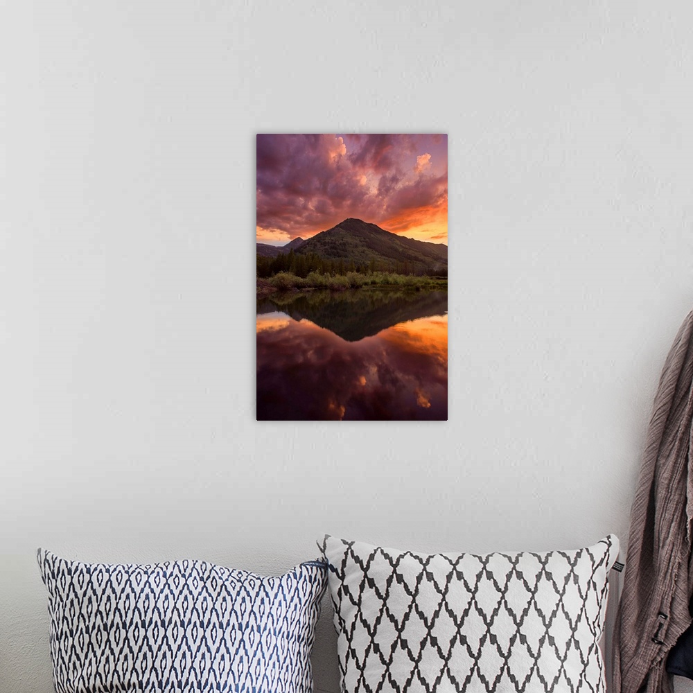 A bohemian room featuring A photograph of a mountain seen under an orange sunset sky.
