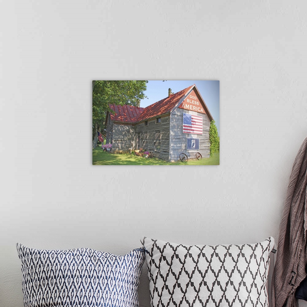 A bohemian room featuring A photograph of a rustic country home with an American flag on the side.