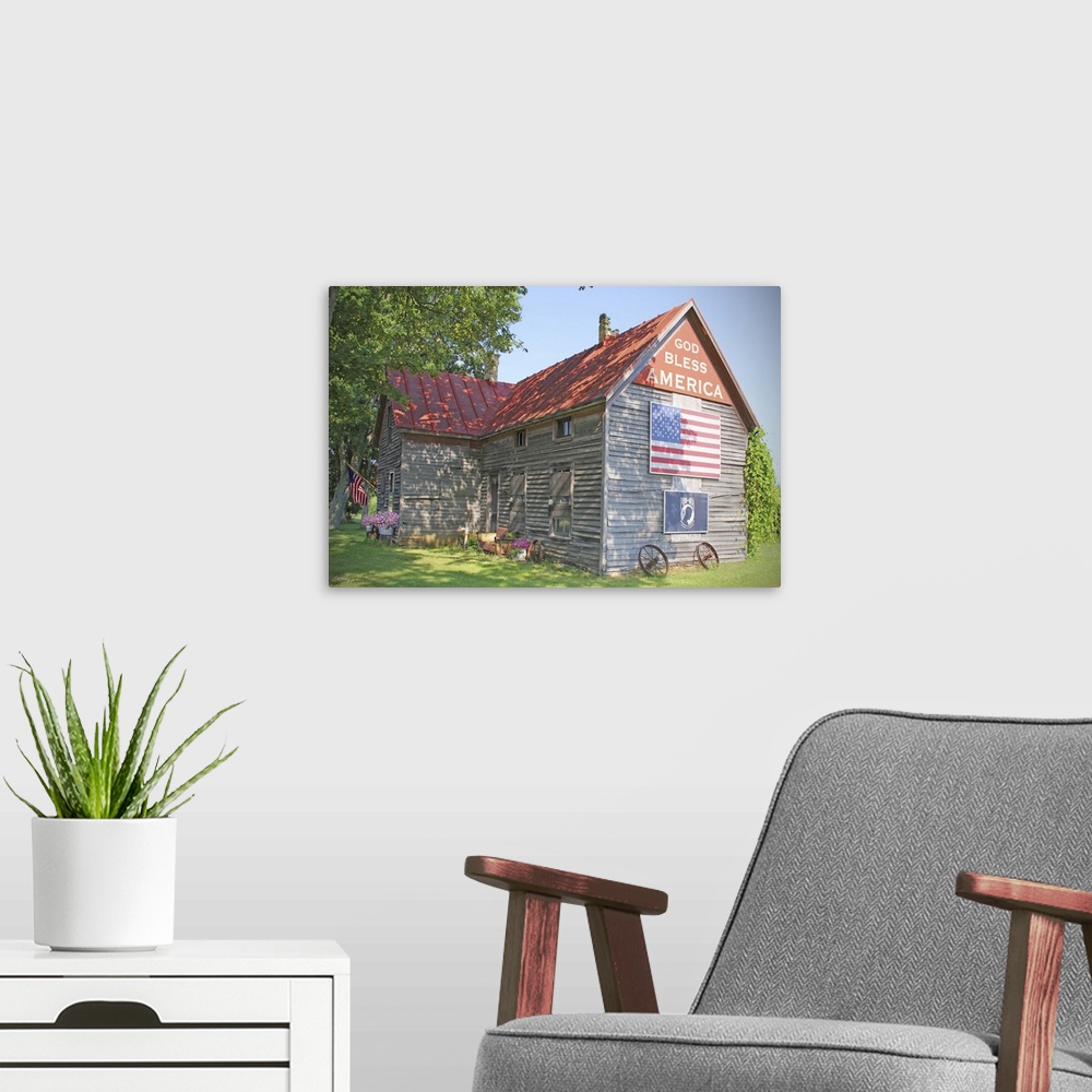 A modern room featuring A photograph of a rustic country home with an American flag on the side.