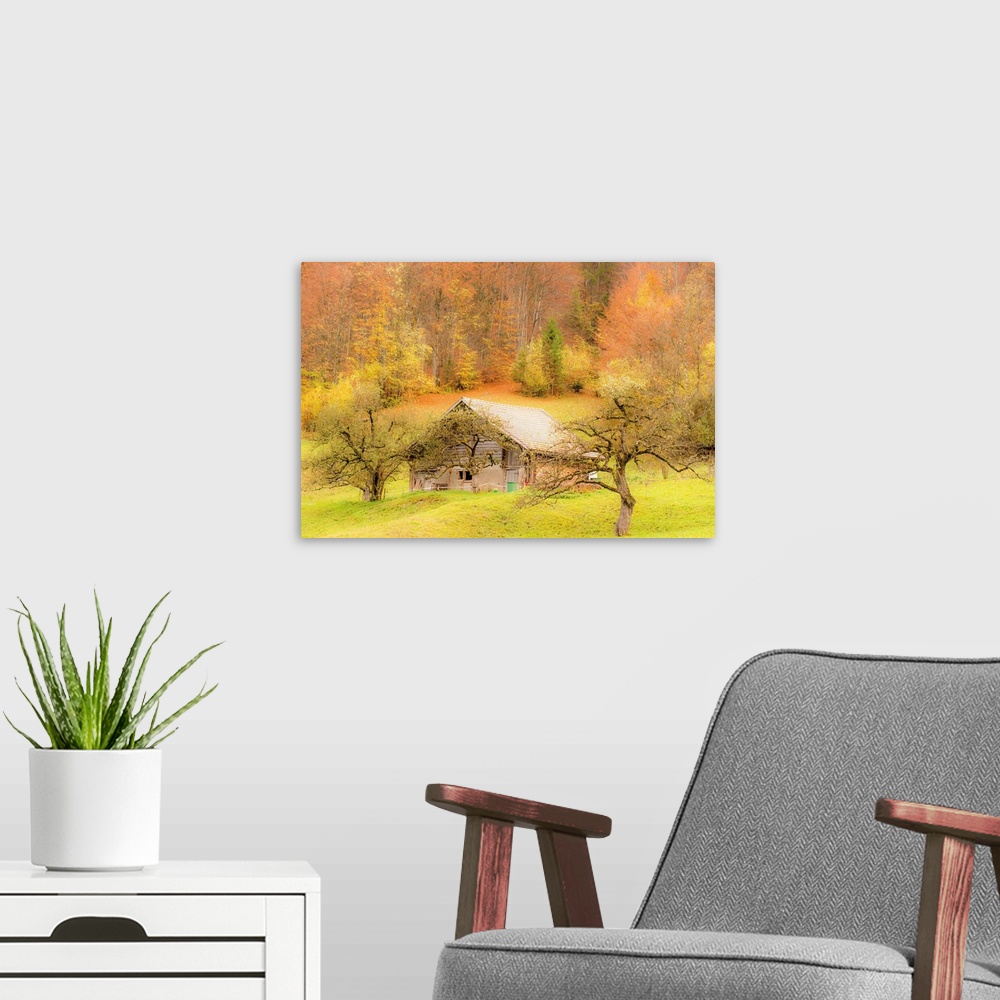 A modern room featuring Landscape photograph of an old barn on a hill surrounded by Autumn trees.