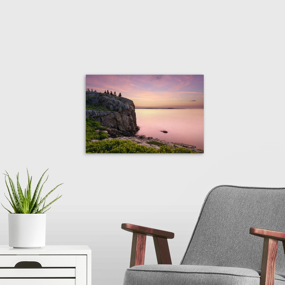 A modern room featuring An artistic photograph of a rocky cliff-side overlooking a sunset drenched seascape.
