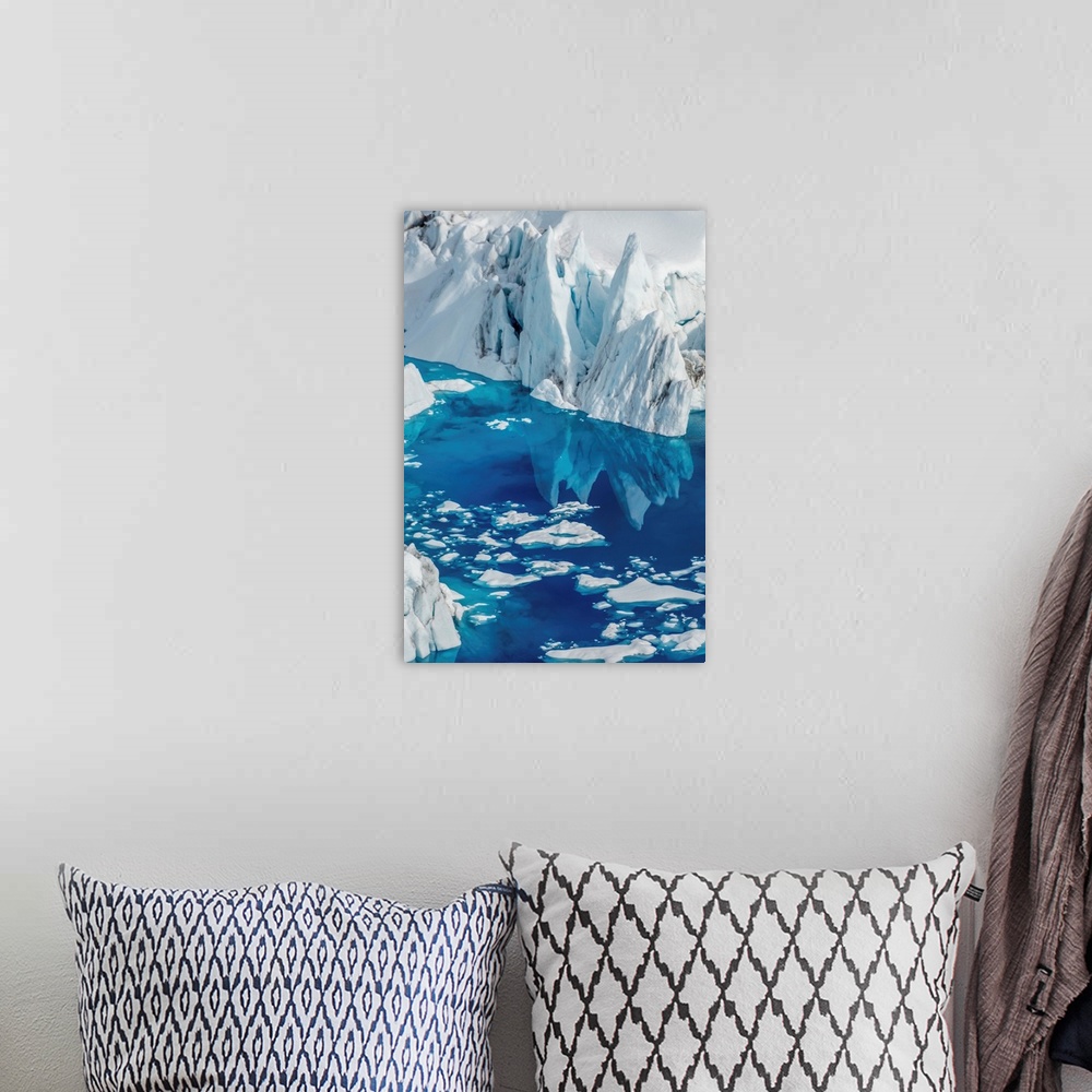 A bohemian room featuring Landscape photograph of an iceberg reflecting onto bright blue water.