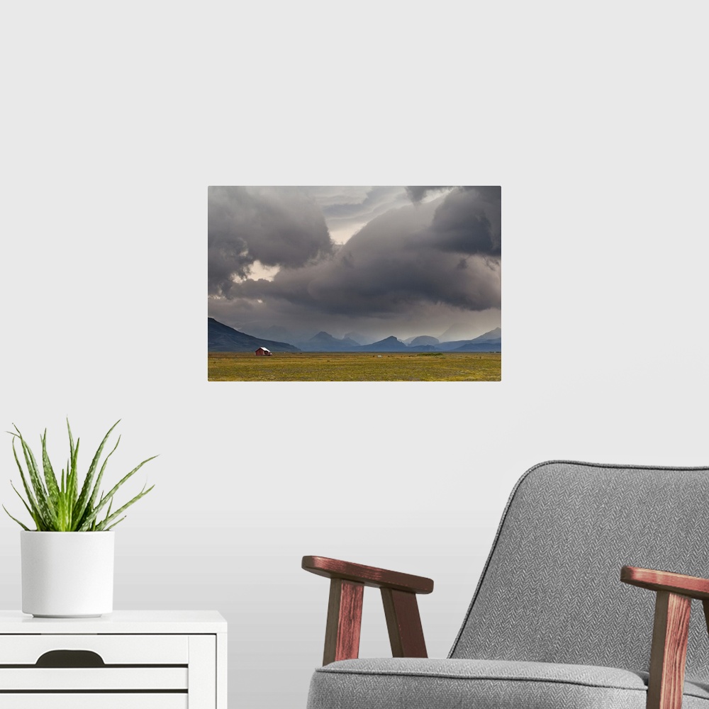 A modern room featuring A photograph of a dramatic cloudscape hanging over an Icelandic landscape.
