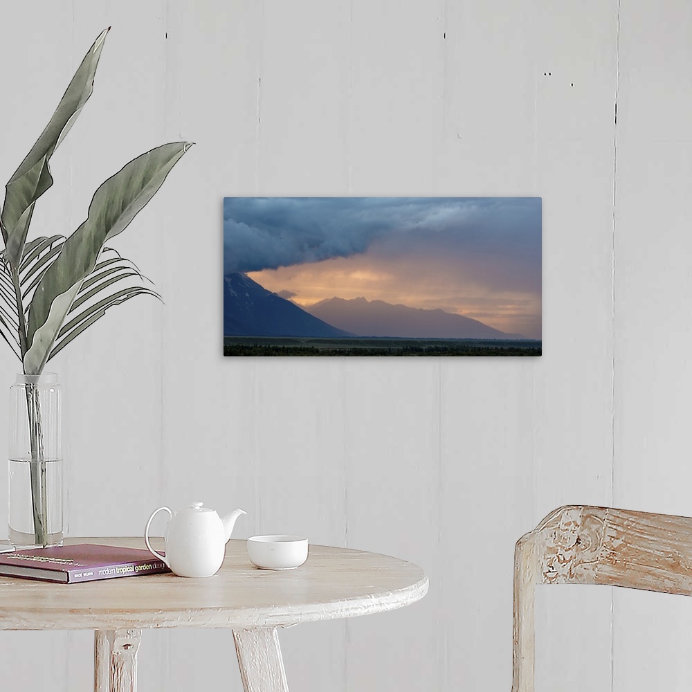 A farmhouse room featuring A photograph of mountain under dramatic clouds illuminated by the sunset.