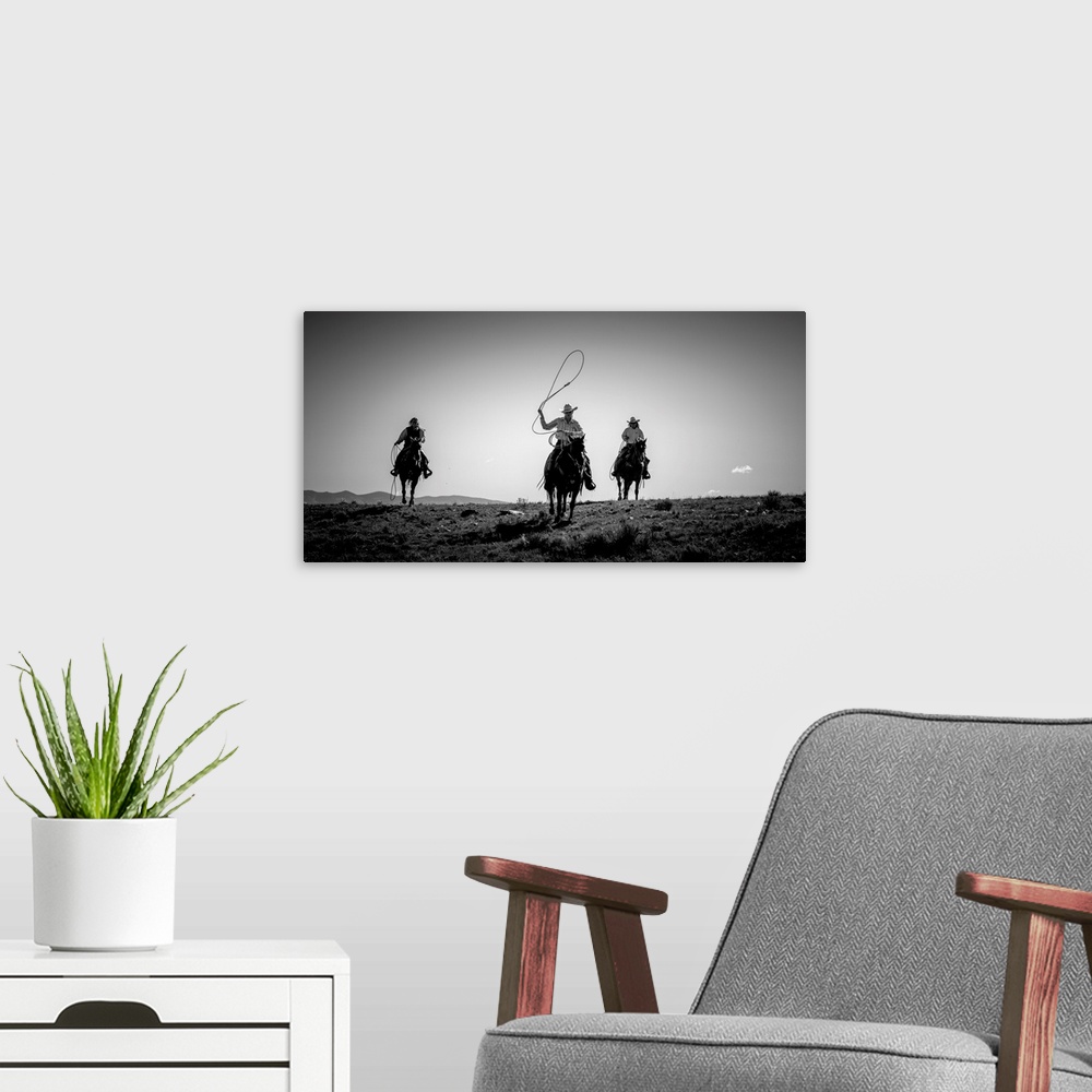 A modern room featuring Black and white photograph of three cow girls on horseback with their lassos out.