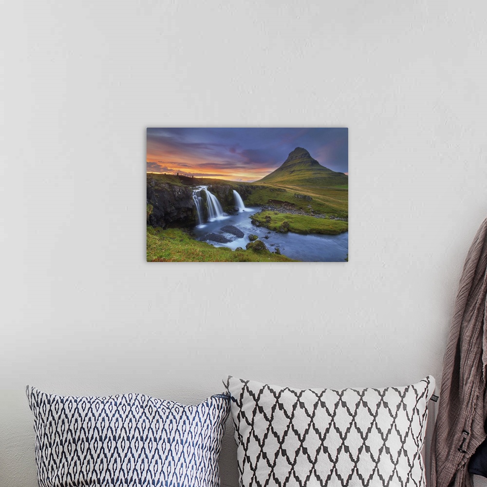 A bohemian room featuring A photograph of an Icelandic landscape with waterfalls to the left and a sunset cloudscape hangin...