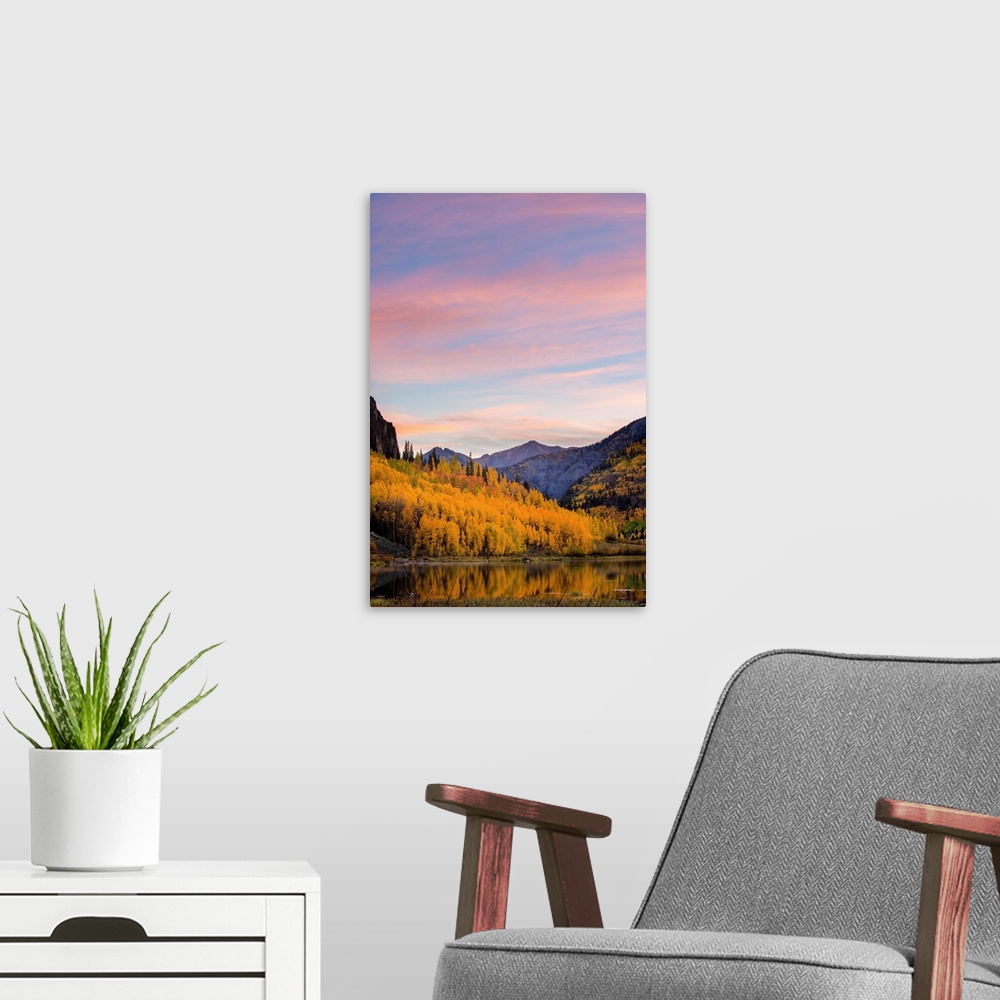 A modern room featuring Landscape photograph of a lake lined with yellow Autumn trees and mountains in the background at ...