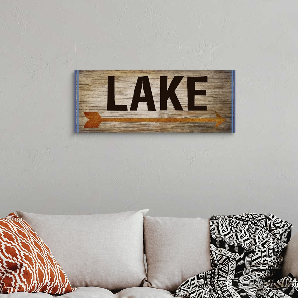 A bohemian room featuring Wooden sign with an orange arrow, 2 blue lines on each side, and the word "Lake" written across it.