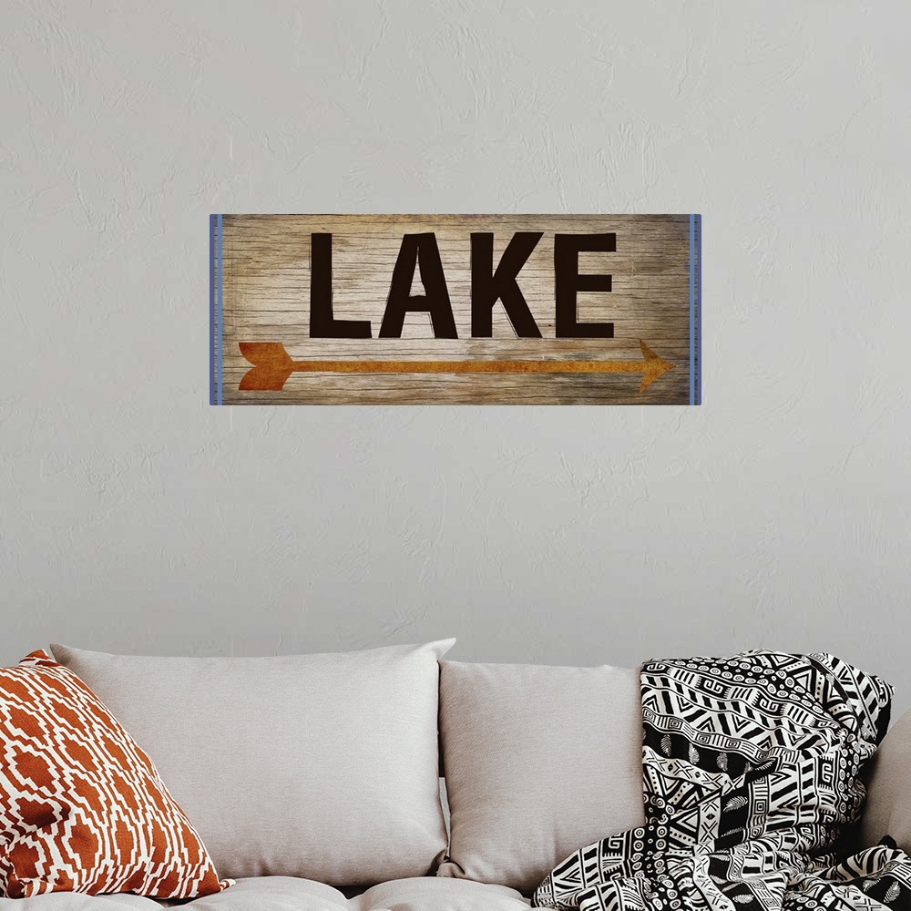 A bohemian room featuring Wooden sign with an orange arrow, 2 blue lines on each side, and the word "Lake" written across it.
