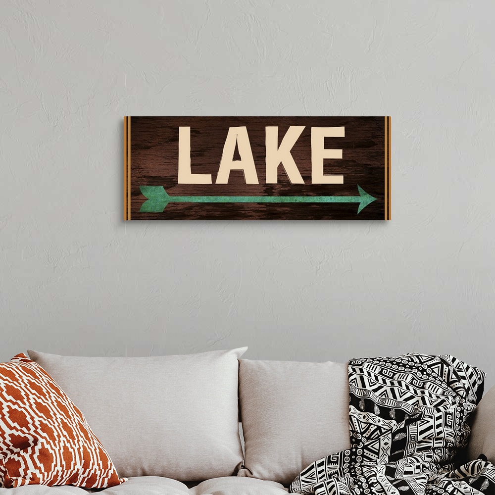 A bohemian room featuring Dark wooden sign with a teal arrow, 2 orange lines on each side, and the word "Lake" written acro...