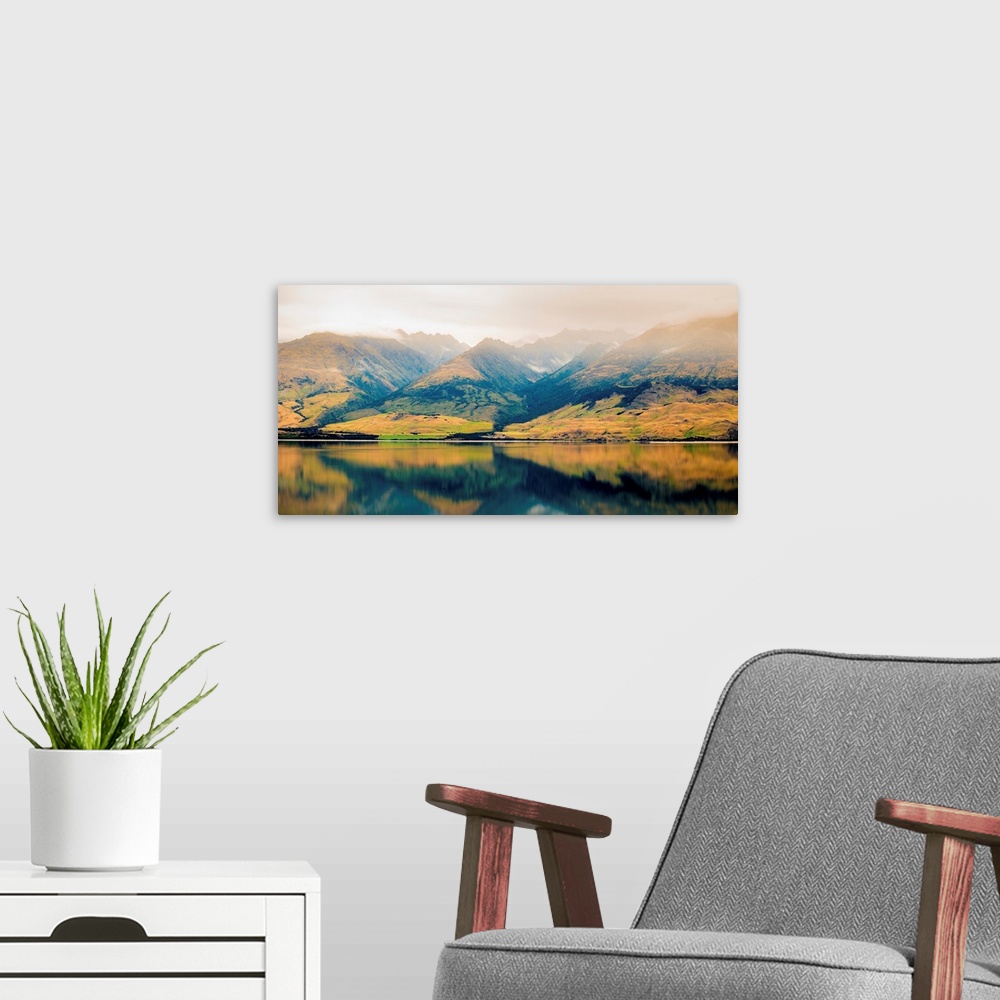 A modern room featuring Landscape photograph of a lake with Autumn covered mountains in the background and a foggy top.