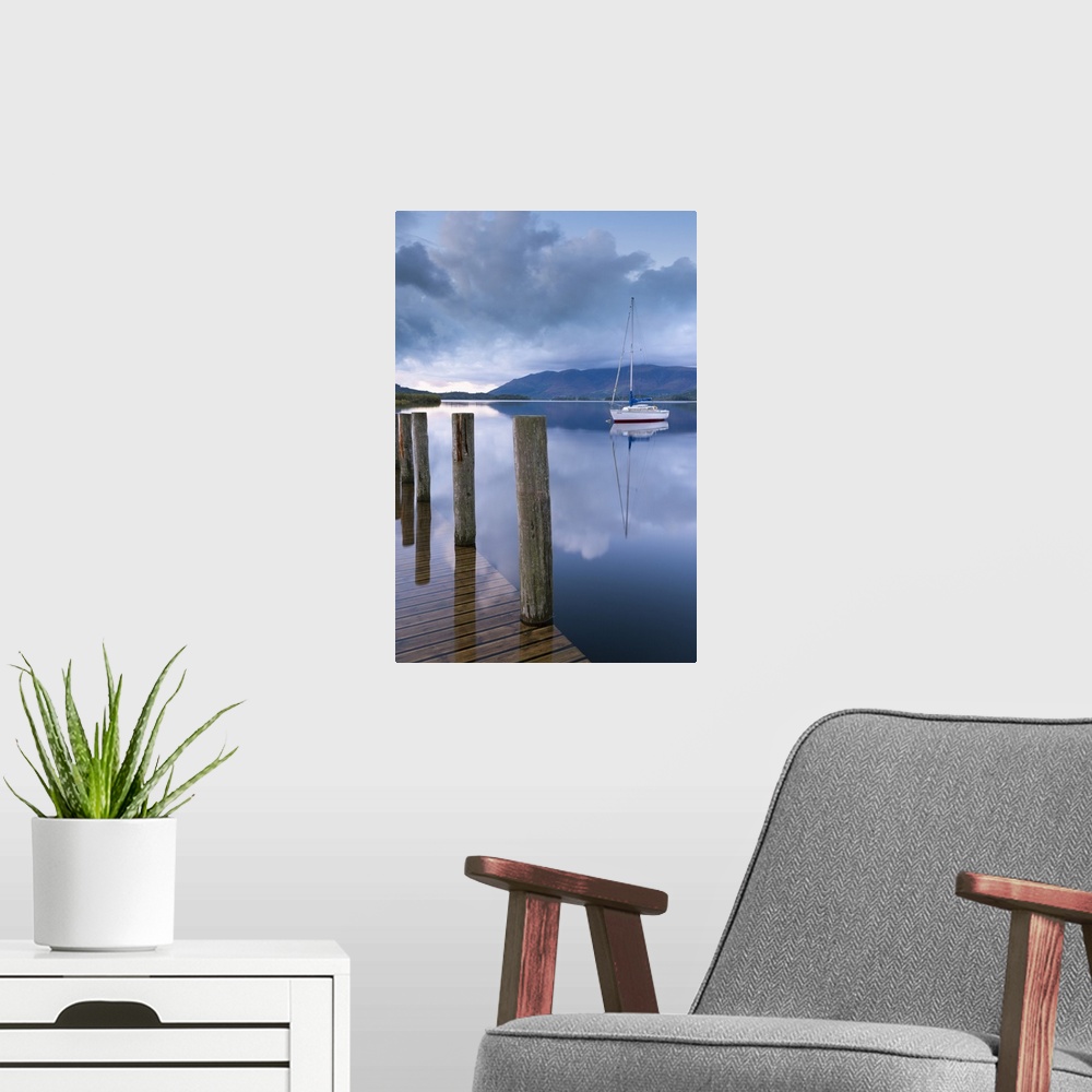 A modern room featuring View from a wooden dock of a boat on a calm lake.