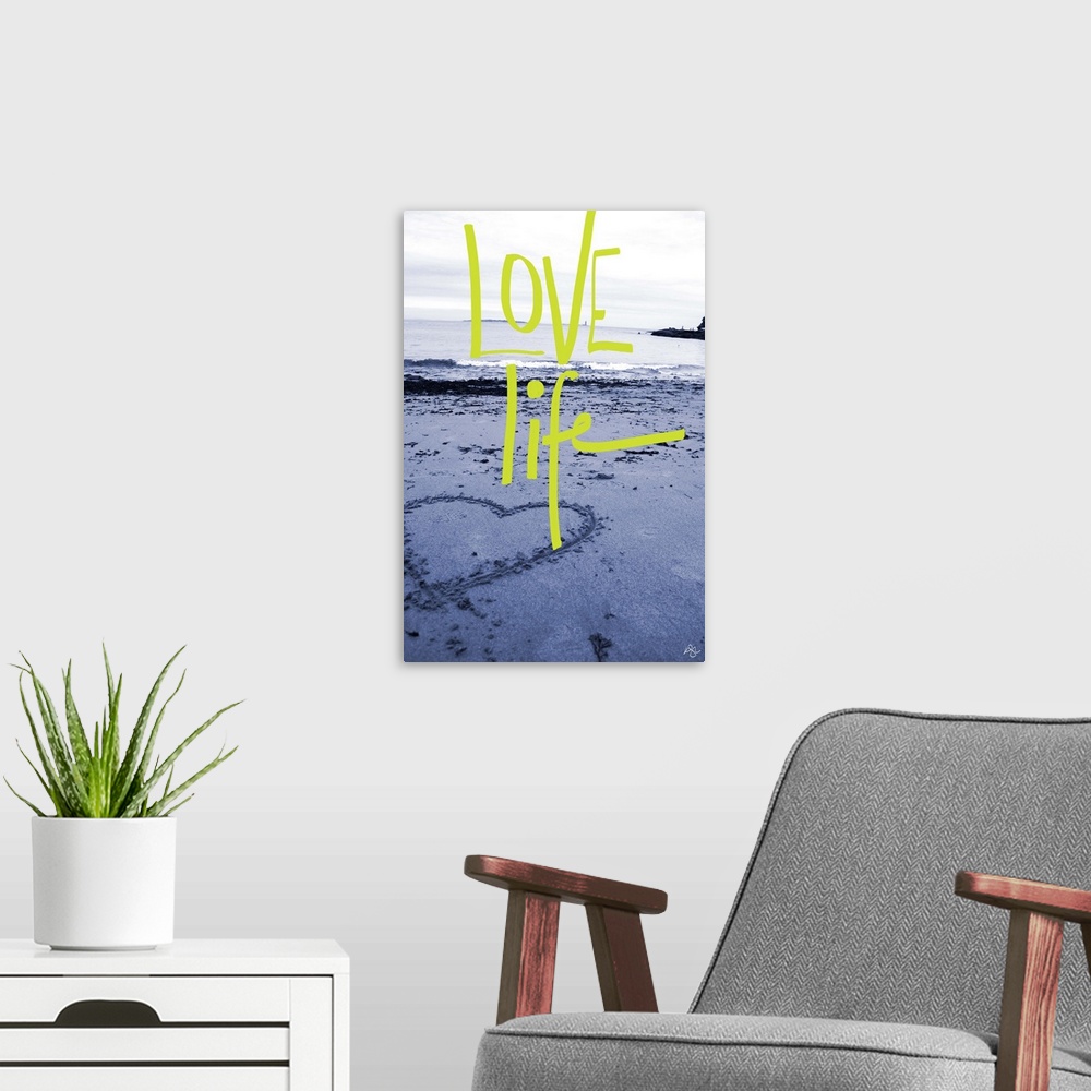 A modern room featuring "Love Life" handwritten over a photograph of a heart drawn in the sand on a beach.