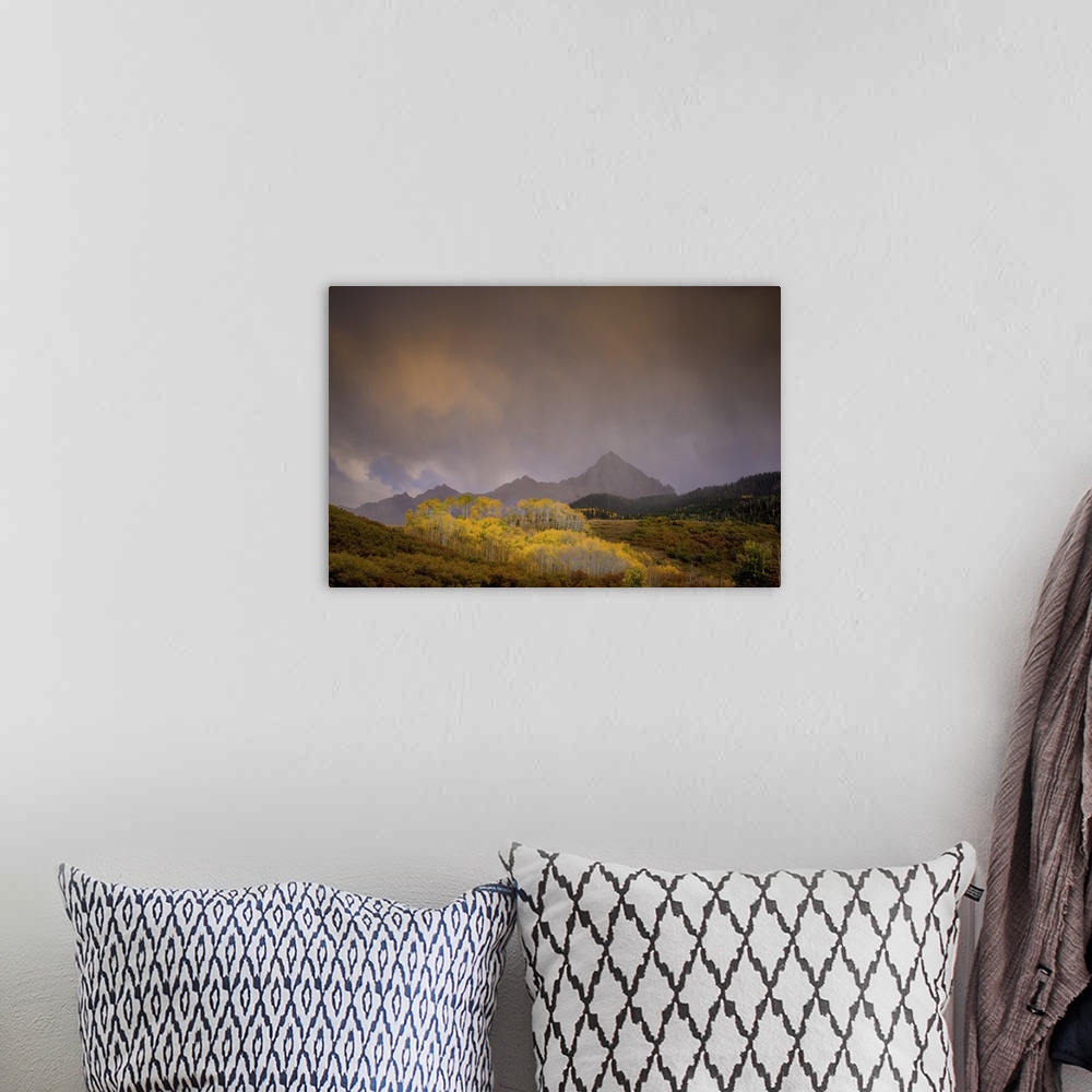 A bohemian room featuring A photograph of a mountain landscape with hazy clouds hanging overhead.