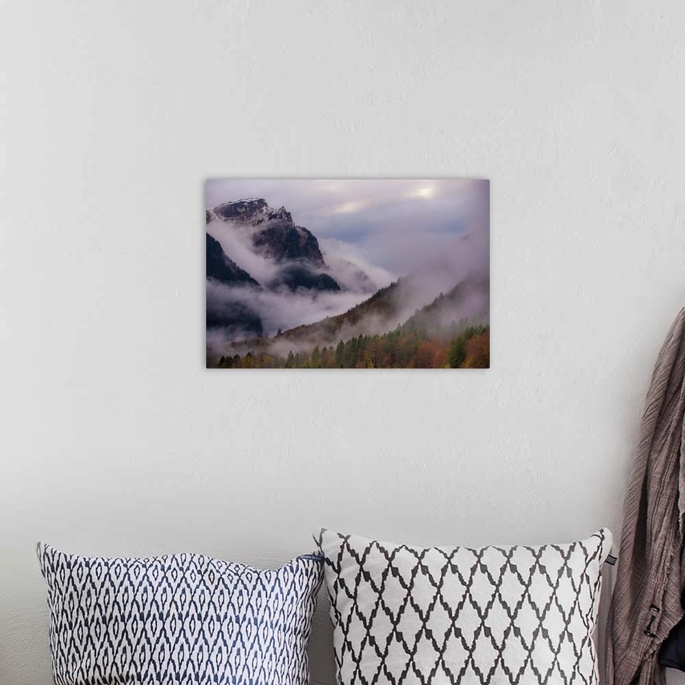 A bohemian room featuring A photograph of a mountain valley covered in deep with thick fog shrouding the area.