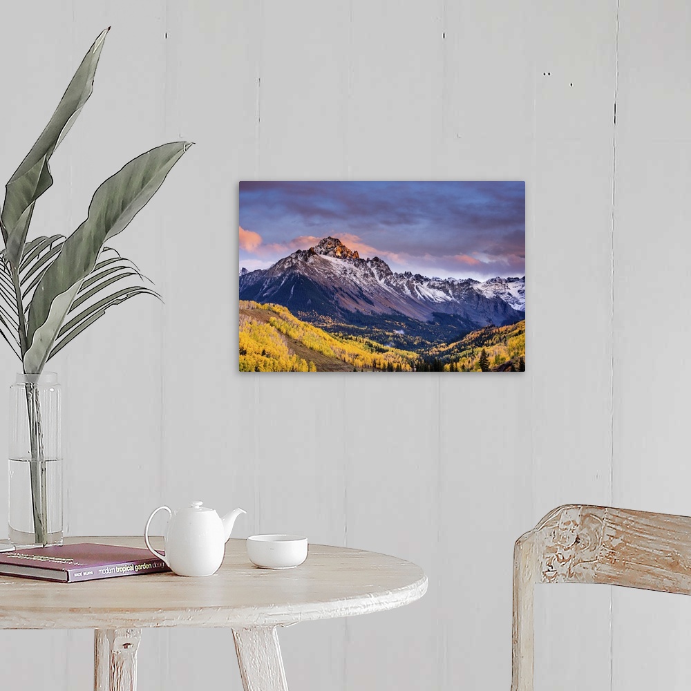 A farmhouse room featuring A photograph of mountain under dramatic clouds illuminated by the sunset.