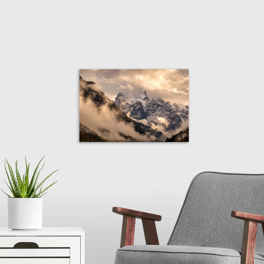 A modern room featuring Beautiful landscape photograph of snowy mountain peaks engulfed in clouds.
