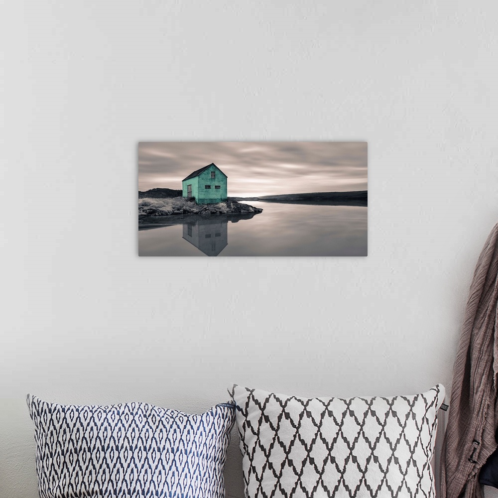 A bohemian room featuring An artistic photograph of a mint colored shack at the edge of a shallow still river.