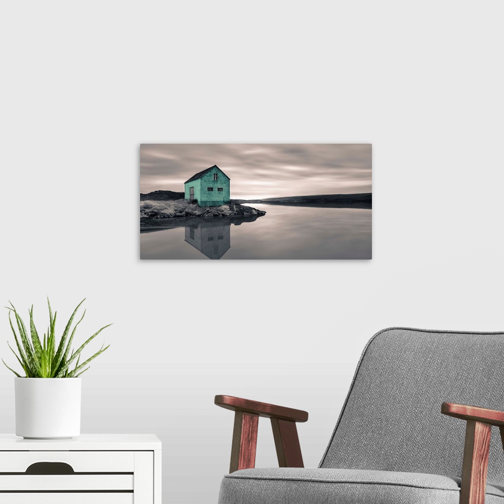 A modern room featuring An artistic photograph of a mint colored shack at the edge of a shallow still river.