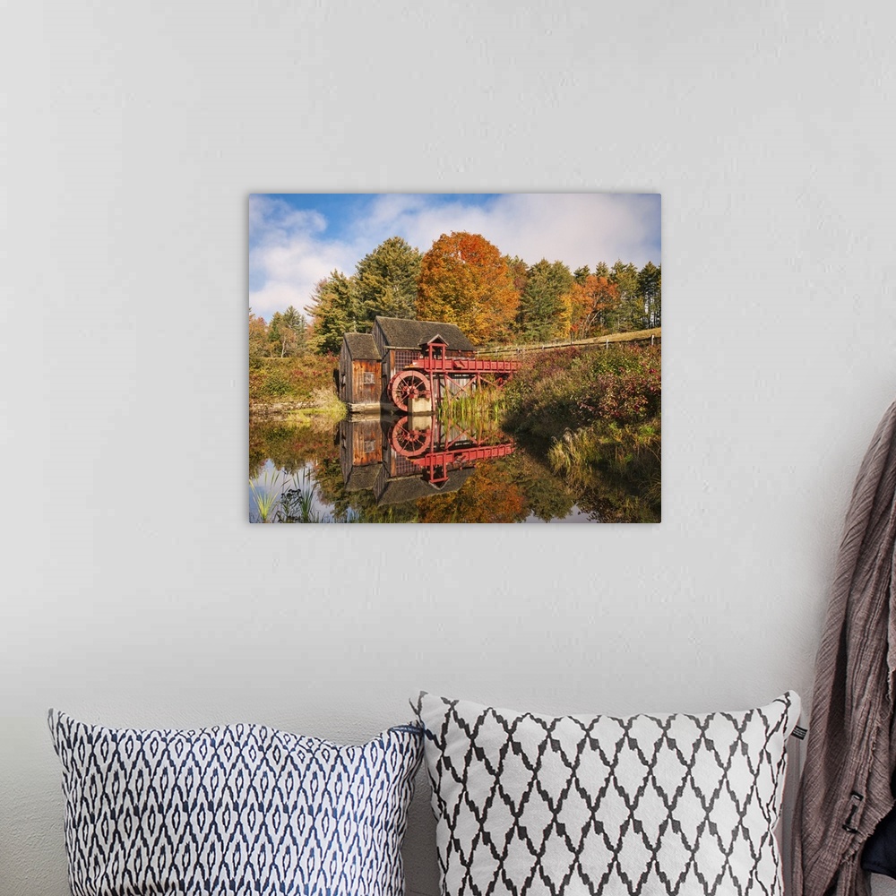 A bohemian room featuring A photograph of a red water mill in the middle of a forest in autumn foliage.