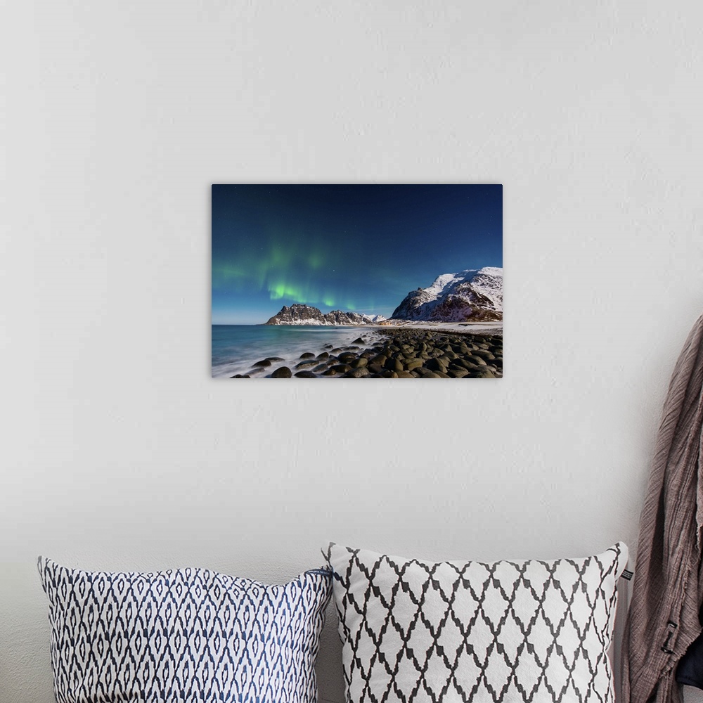A bohemian room featuring A photograph of a snow covered mountain range under a night sky with northern lights above.