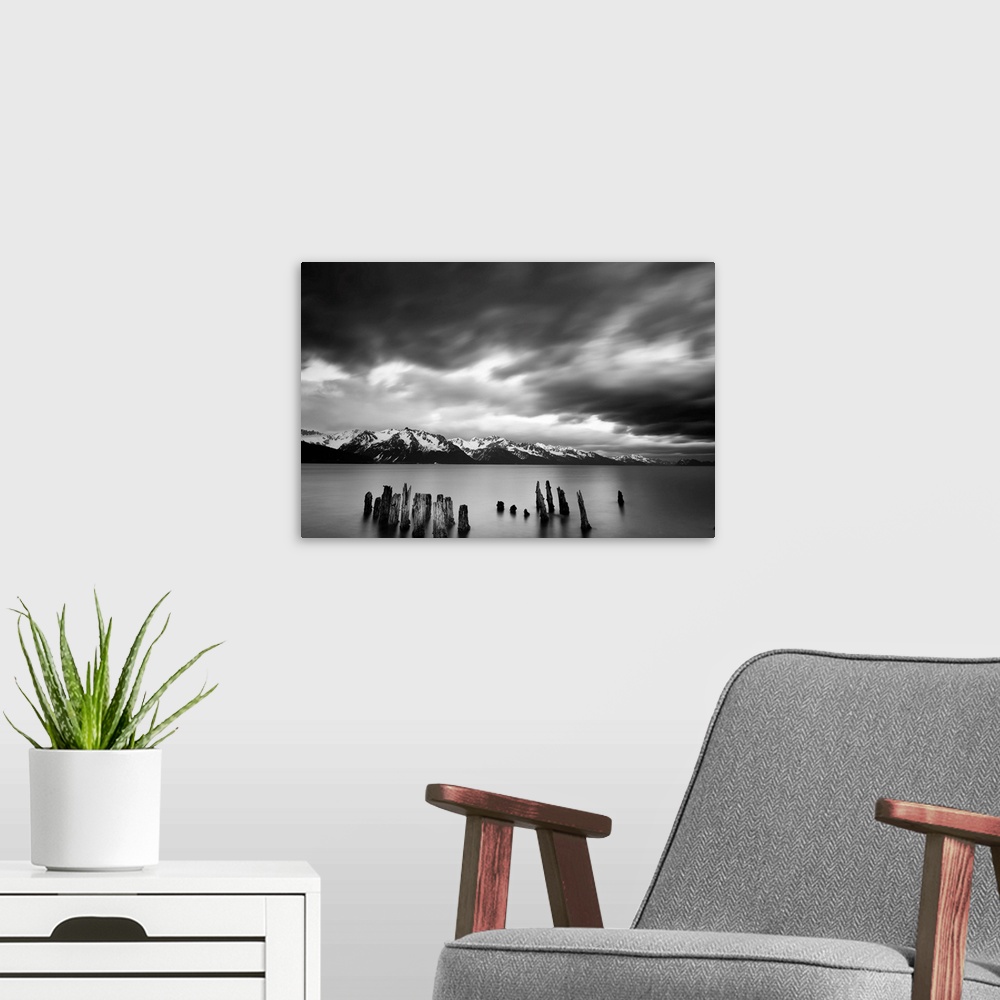 A modern room featuring Long exposure black and white landscape photograph of a quiet lake with snow capped mountains in ...