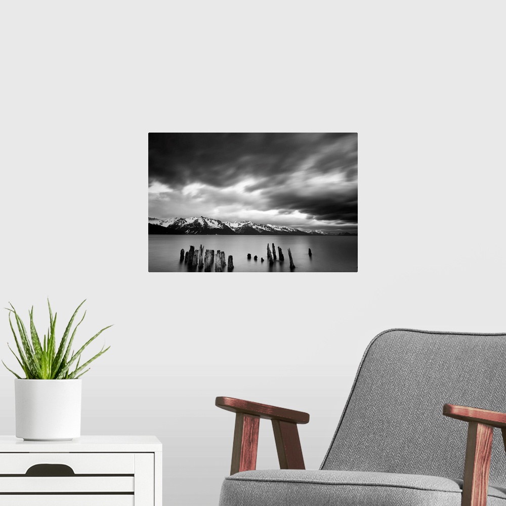 A modern room featuring Long exposure black and white landscape photograph of a quiet lake with snow capped mountains in ...